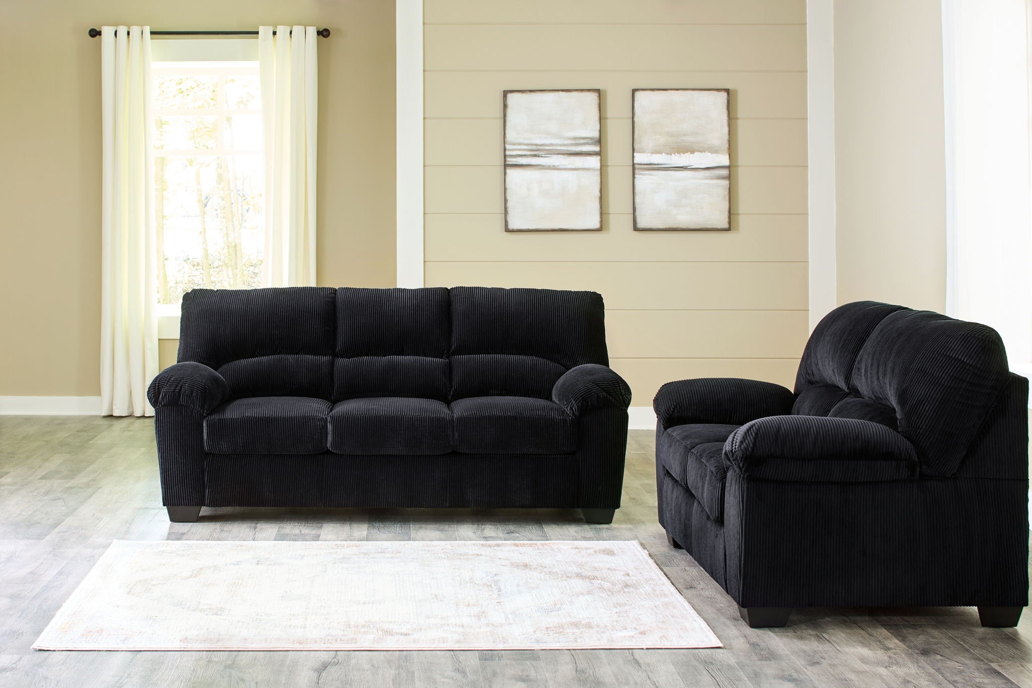 Black sofa with cushioned back and rounded arms, plus recliner