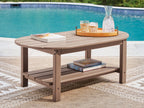 Light brown oval outdoor coffee table with slatted top and lower shelf, side view