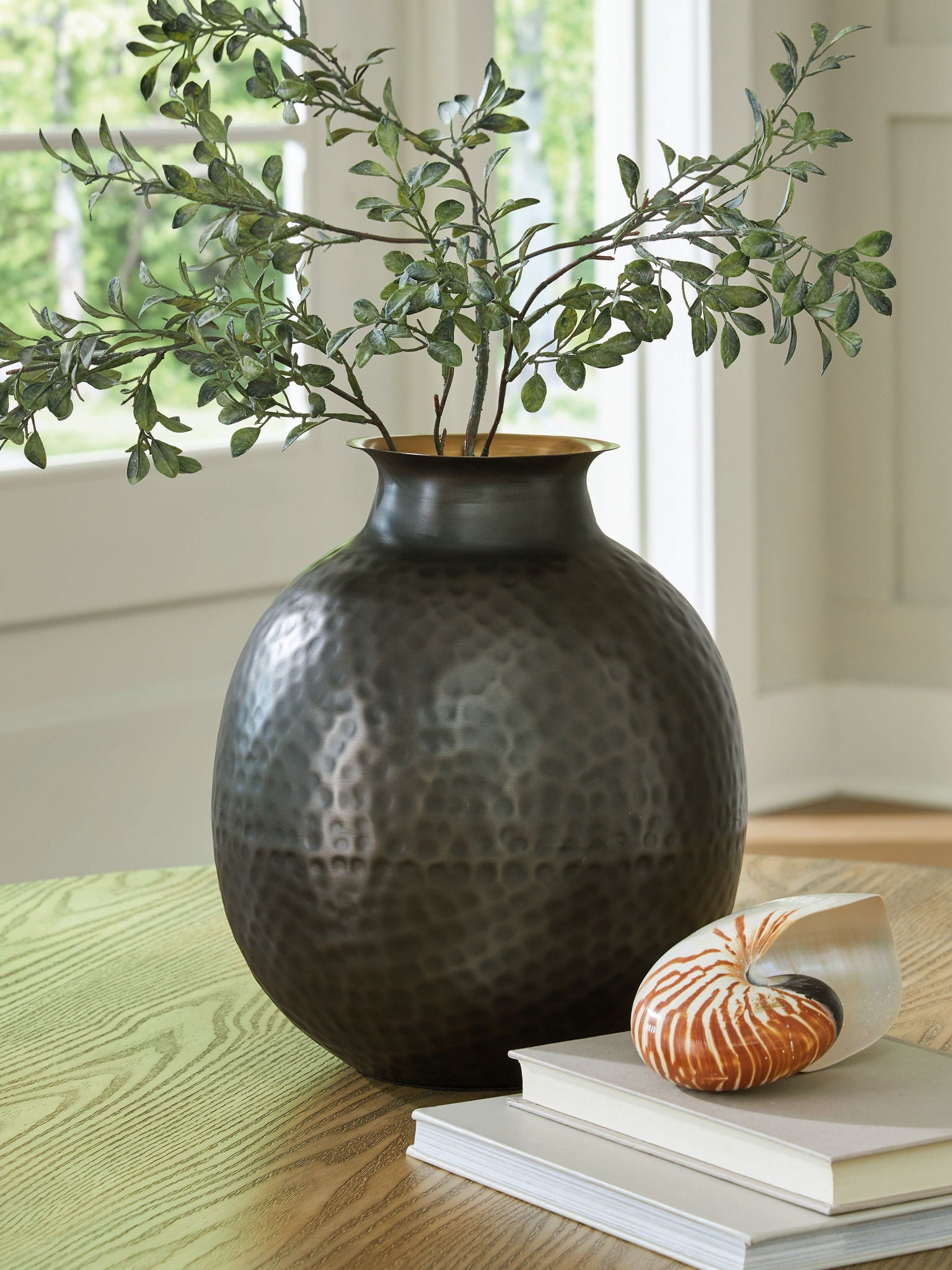 Dark gray hammered ceramic vase on table with gold-toned interior rim