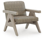 Beige woven rocking lounge chair with padded armrests and angled wooden base