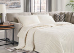 Sofa sleeper with pebble gray upholstery and plush white bedding laid out on top