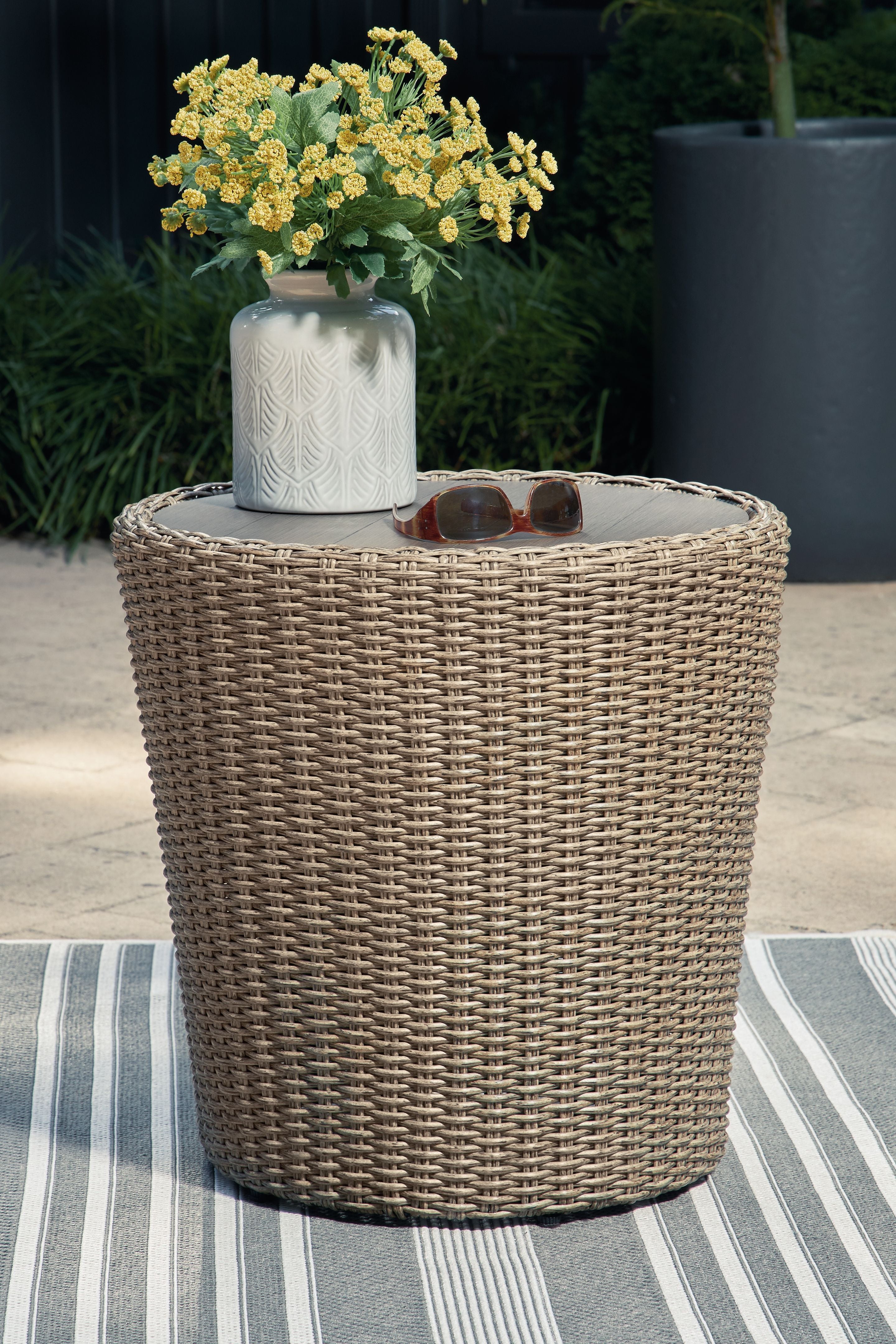 Beige round end table with tall woven wicker sides and round tabletop.