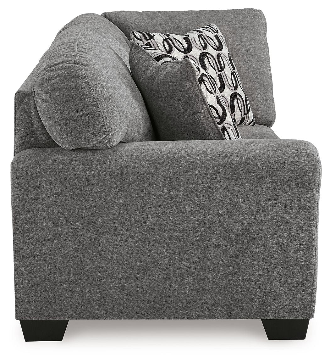 Gray corner wedge sofa chaise with rounded arms and patterned back throw pillow