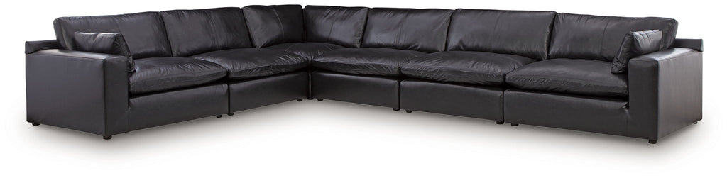 Black leather-look sectional sofa with multiple connected chaise sections and back pillows