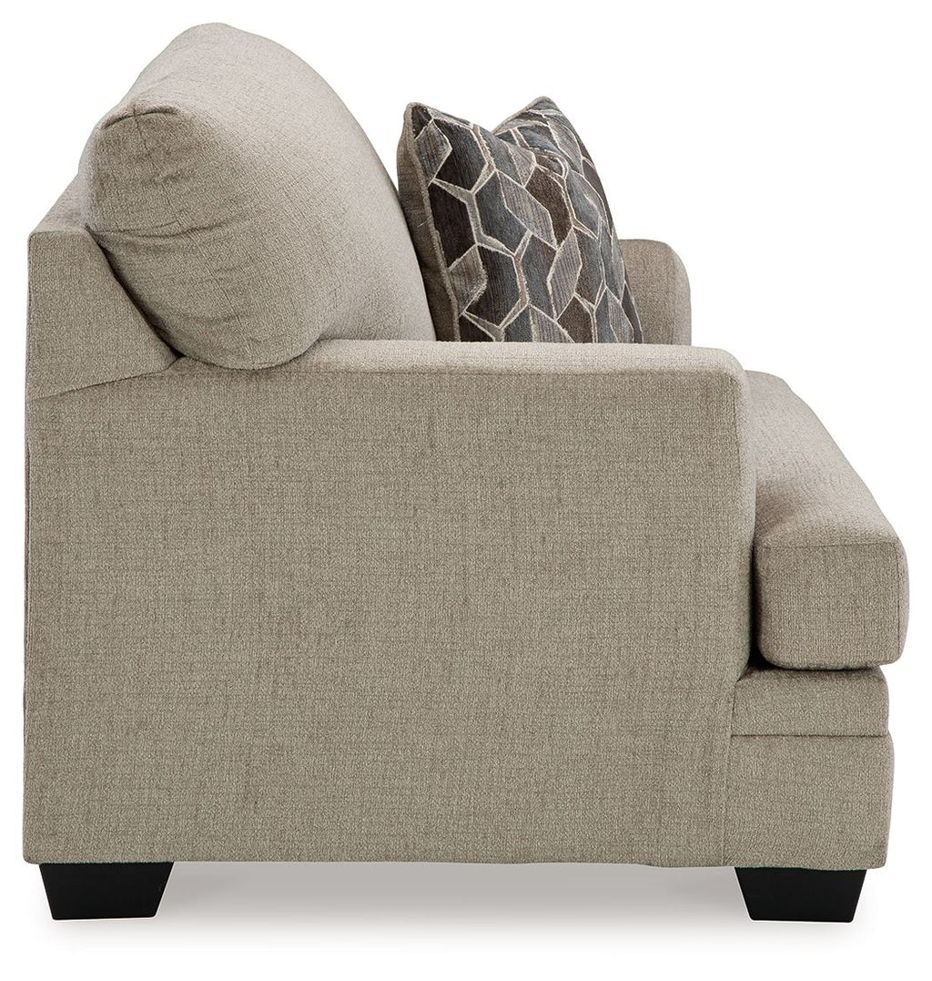 Brown chair-and-a-half armchair with geometric throw pillow and cushioned seat