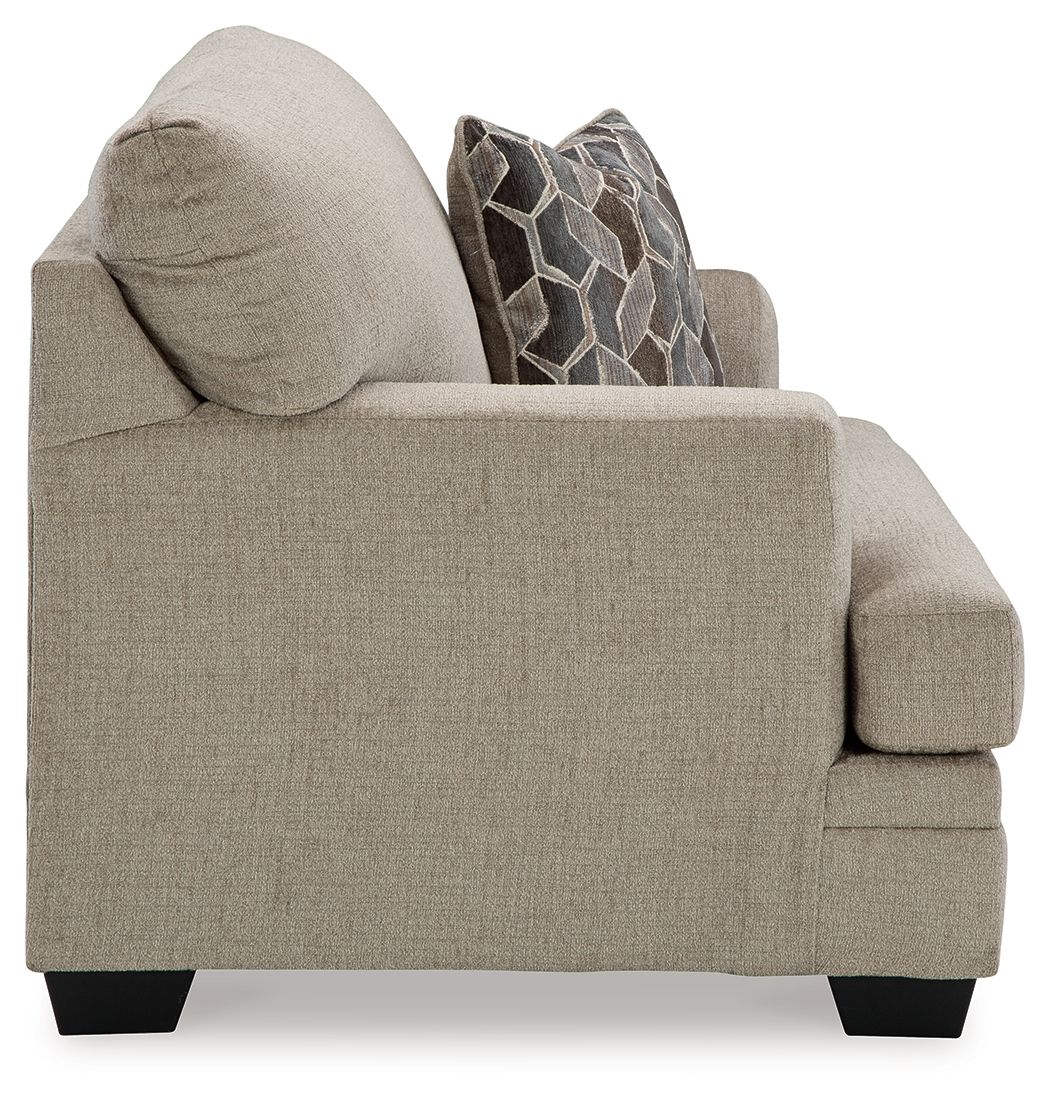 Brown chair-and-a-half armchair with geometric throw pillow and cushioned seat