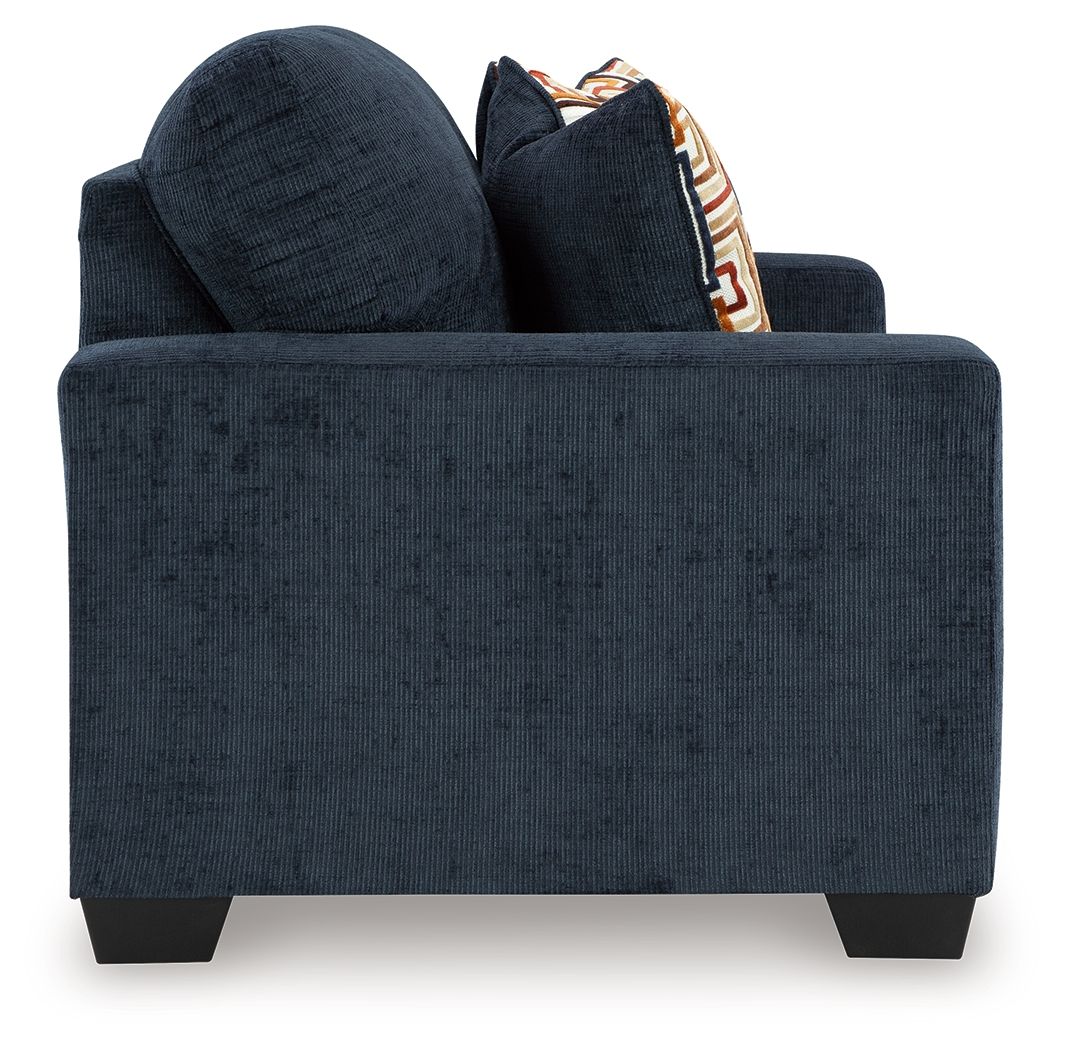 Dark navy loveseat with two decorative geometric throw pillows and boxed front.