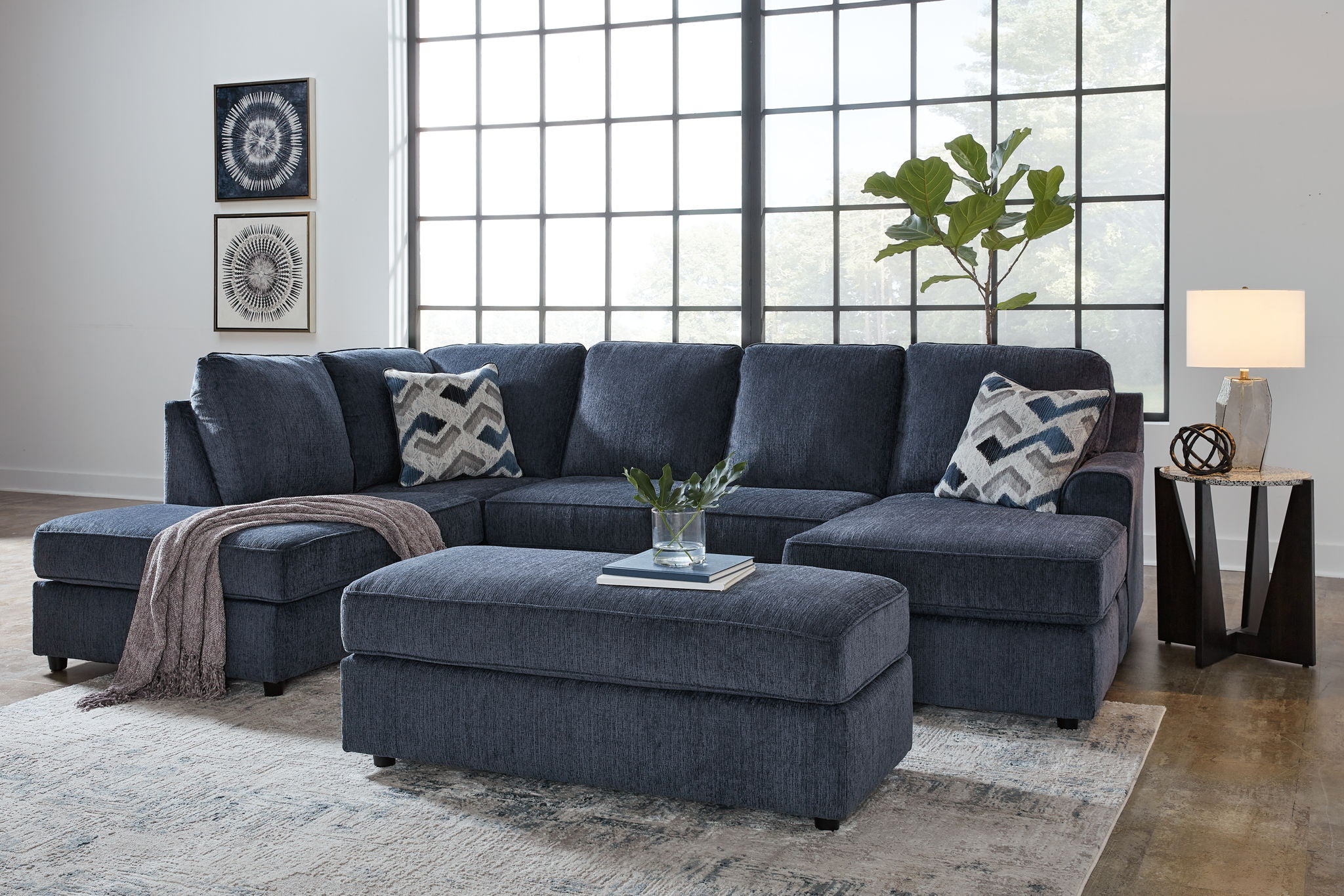 Blue sectional sofa with ottoman and patterned pillows, tufted back cushions