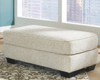 Sandstone upholstered ottoman with cushioned top seam and dark legs