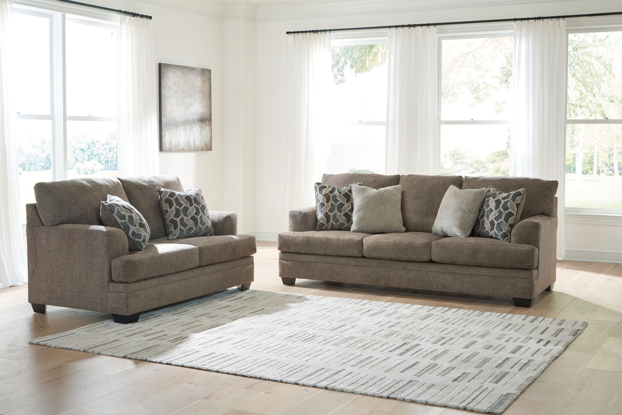 Light brown sofa and loveseat set with patterned accent pillows