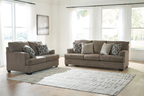 Light brown sofa and loveseat set with patterned accent pillows