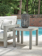 Outdoor gray side table with stone-look top and four legs on a patio