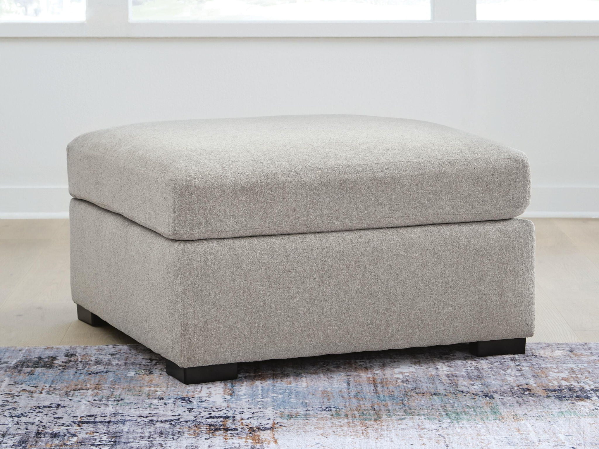 Upholstered ottoman with wide seat and square base, light gray fabric, dark legs