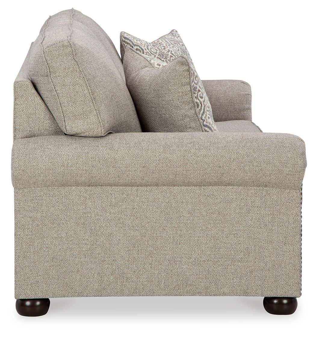 Queen sofa sleeper with light gray upholstery, tufted arms, and two accent pillows