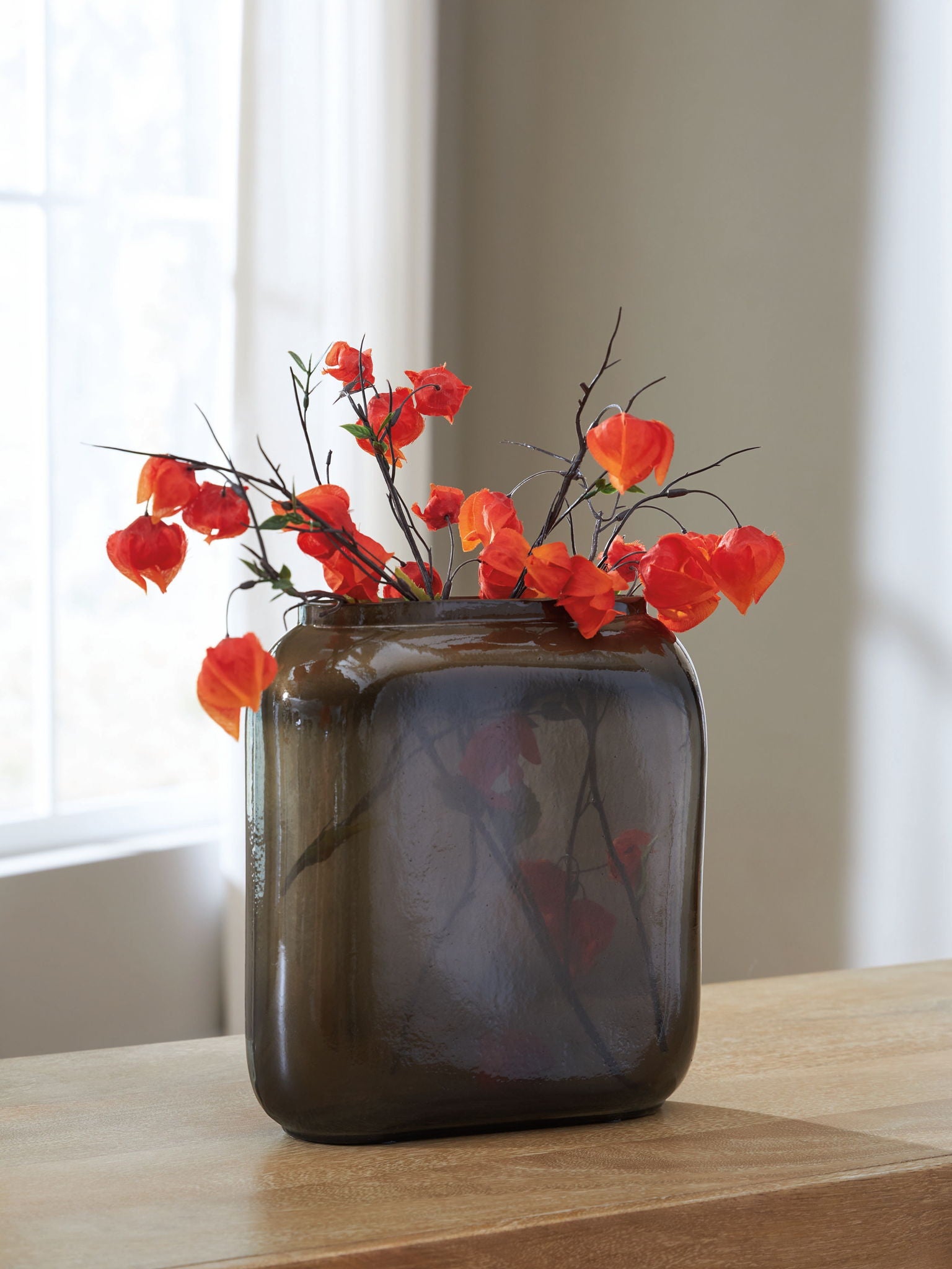Sumner vase with dark brown glossy glass, filled with red flowers