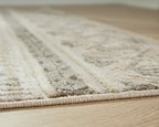 Beige rug close-up with textured pile and distressed pattern sections