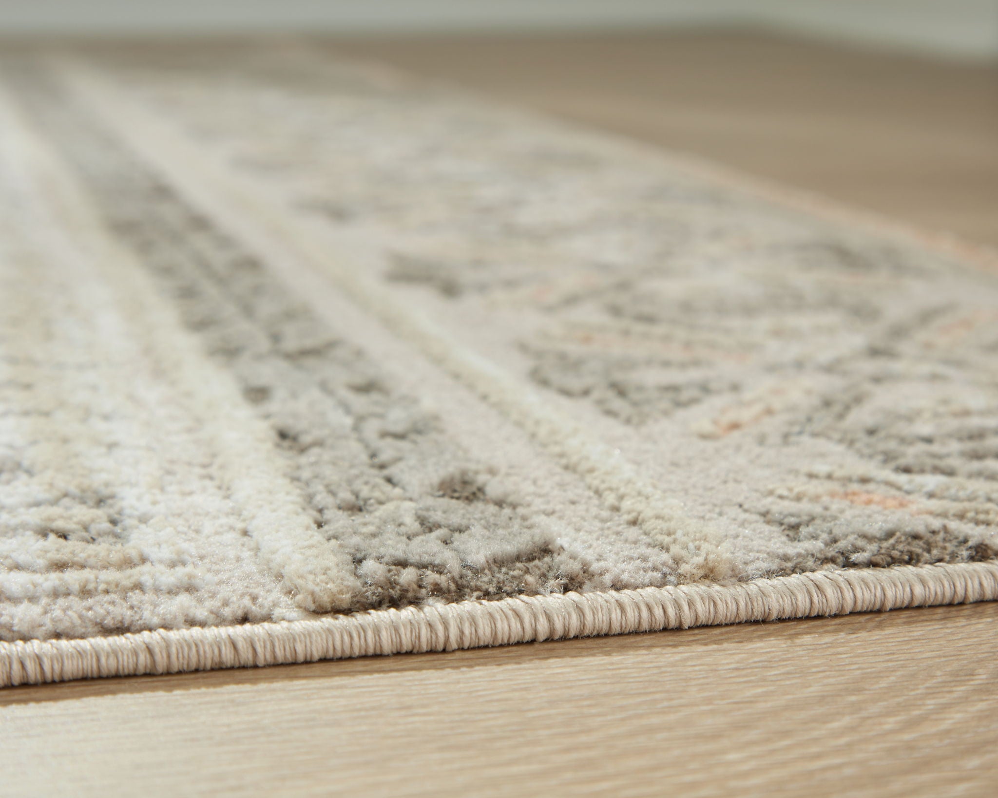 Beige rug close-up with textured pile and distressed pattern sections
