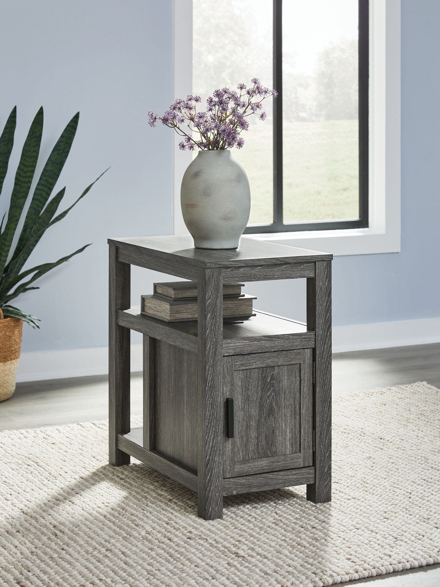 Chair side end table with open shelf and one-door cabinet, dark gray wood, black pull.