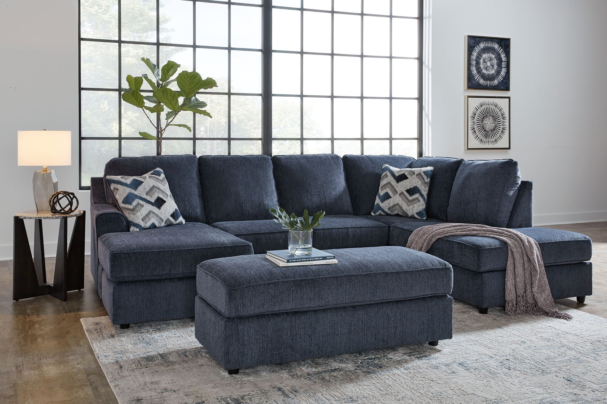Blue sectional sofa with ottoman, tufted seat cushions and patterned pillows