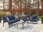 Outdoor seating set with navy loveseat, two armchairs, and gray-framed table with glass top