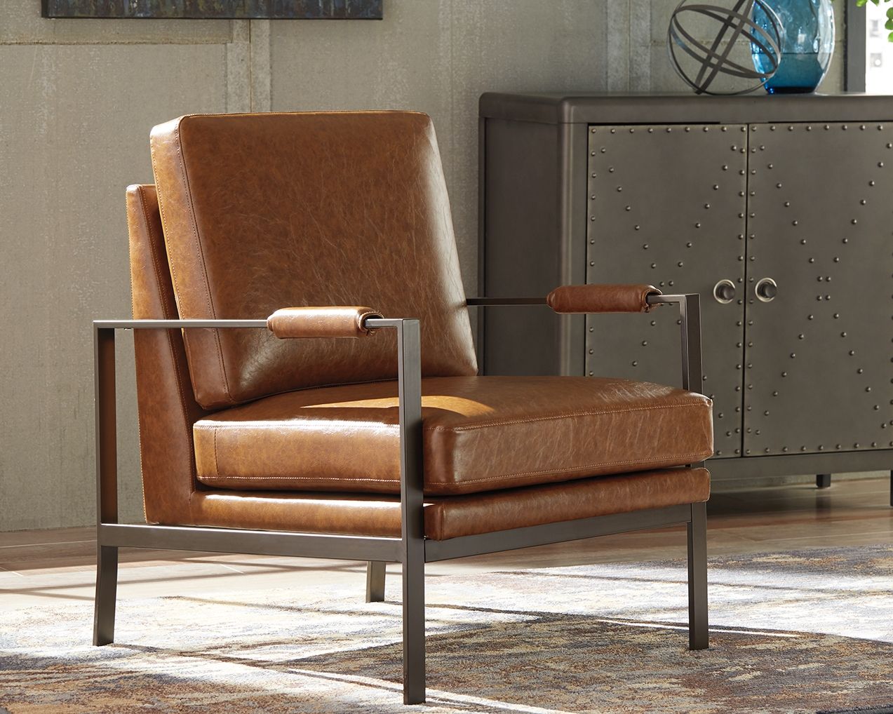Brown leather-look accent chair with upholstered seat, backrest, and armrests on dark frame.
