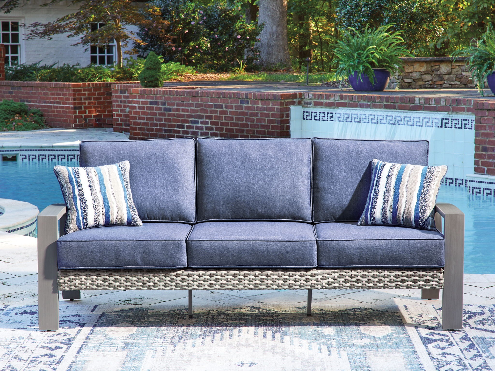 Blue outdoor loveseat sofa with two striped pillows and thick cushioned backrest