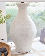 Close-up of antique white textured ceramic vase-shaped lamp base beneath fabric shade