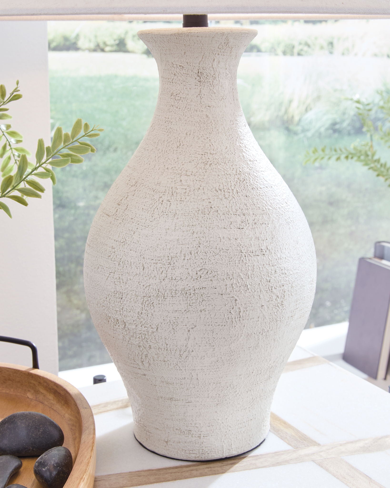 Close-up of antique white textured ceramic vase-shaped lamp base beneath fabric shade