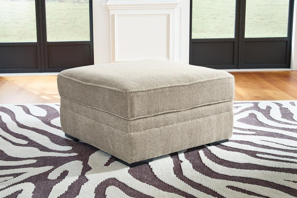 Light beige fabric storage ottoman with hinged top and dark legs