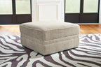 Light beige fabric storage ottoman with hinged top and dark legs