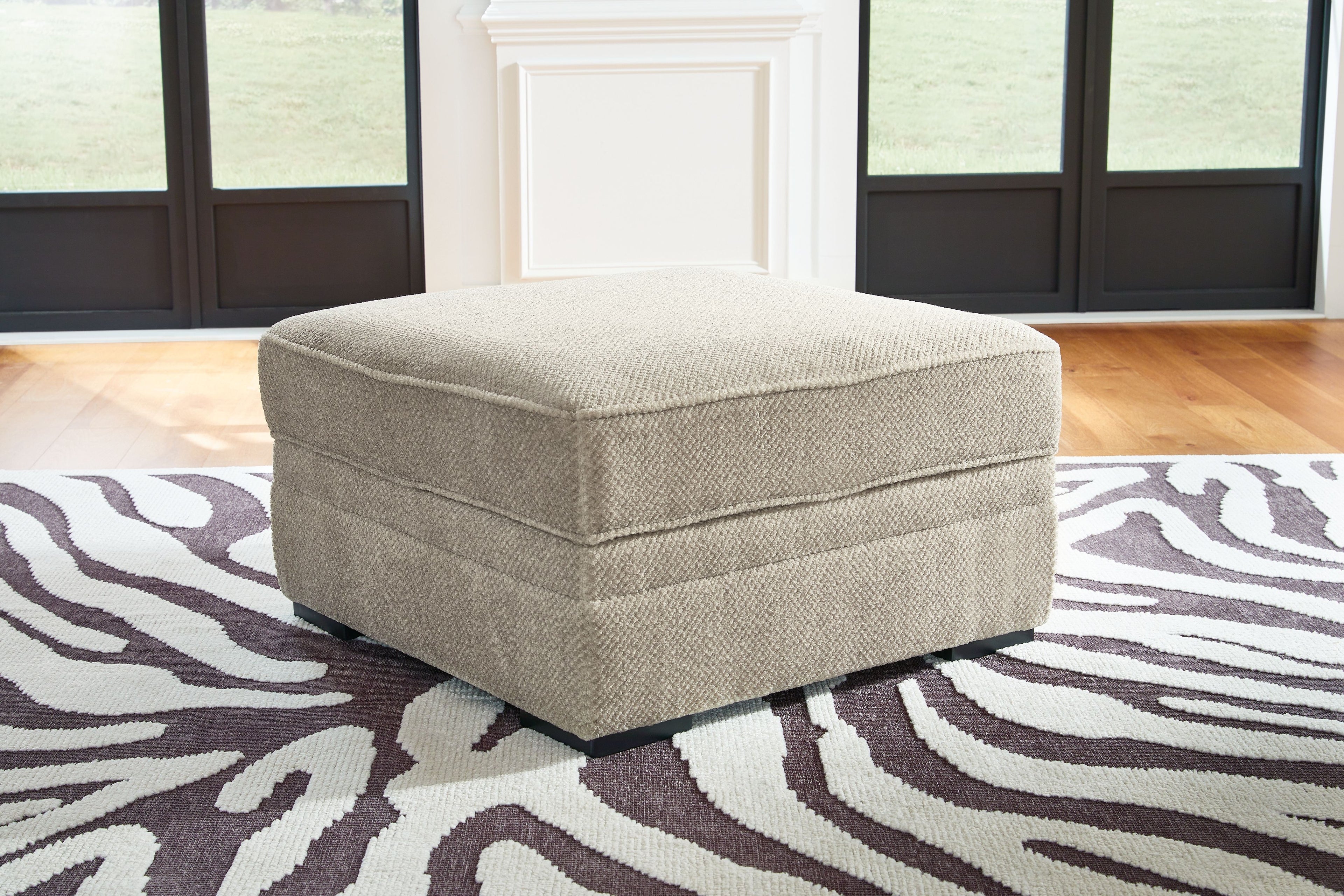 Light beige fabric storage ottoman with hinged top and dark legs