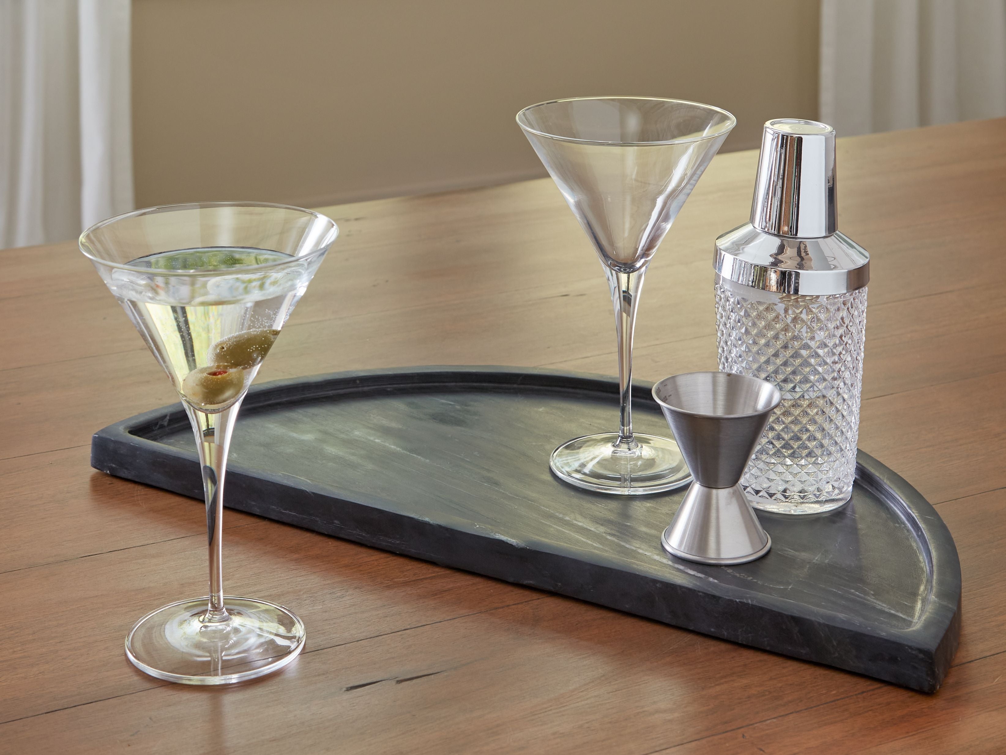 Black serving tray with oval basin, holding cocktails, cups, and a bottle.