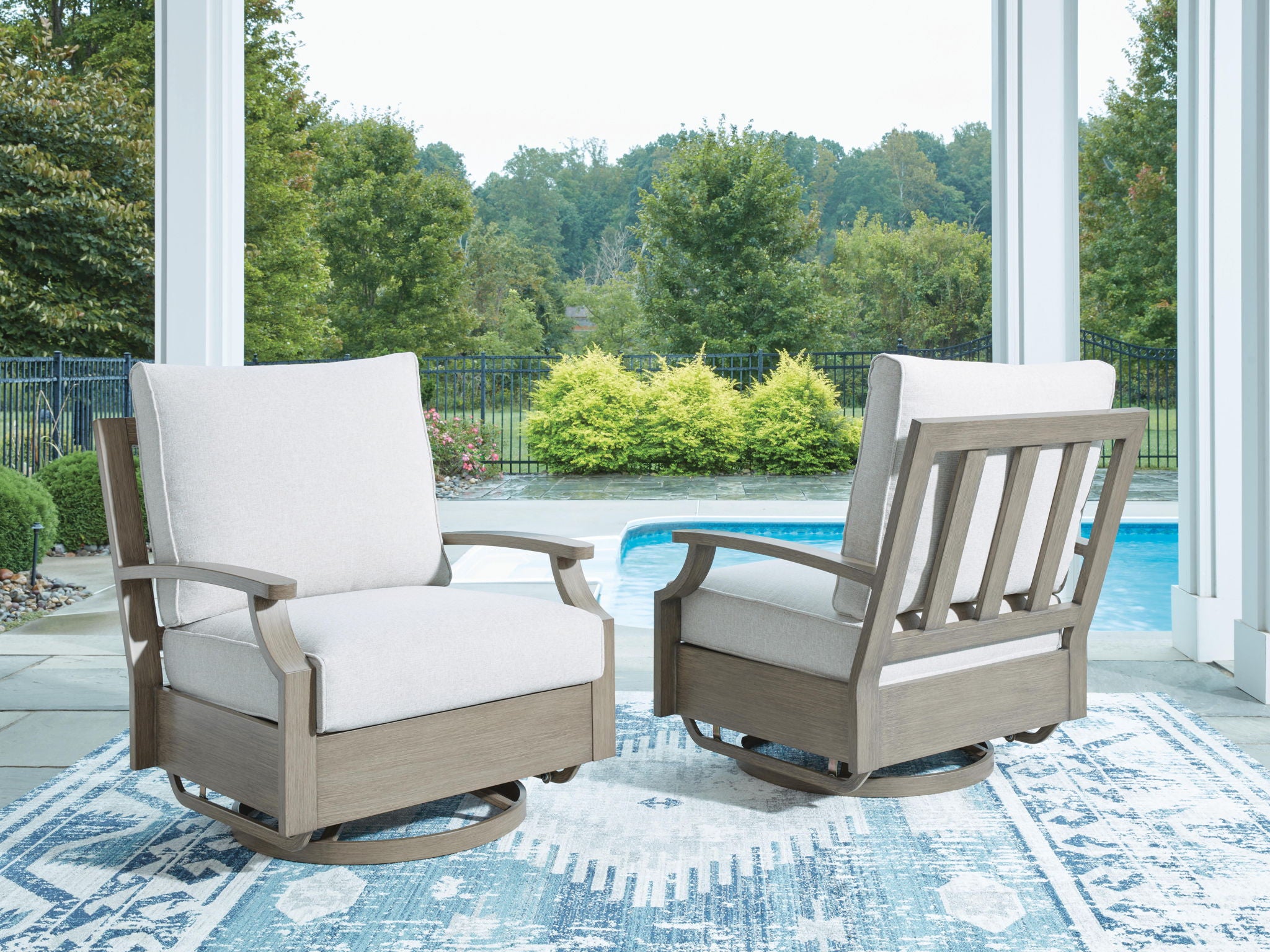 Swivel glider chair with light beige cushion and dark brown frame on outdoor patio