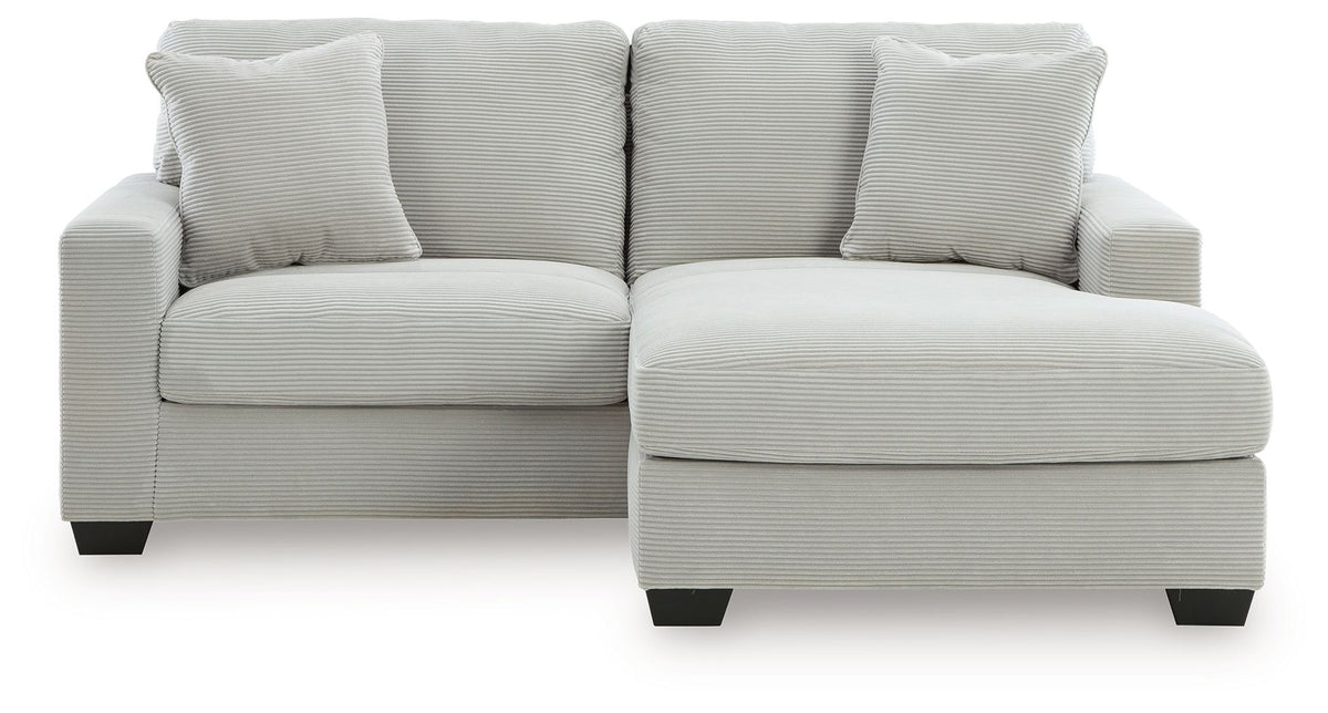 White sofa with chaise-style ottoman and three back pillows, square arms