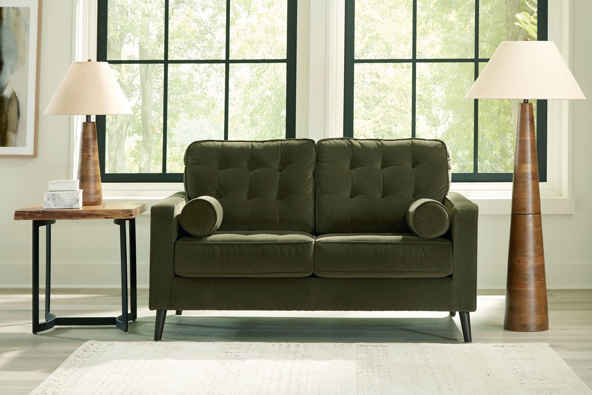 Olive green tufted loveseat with rounded arms, two bolster pillows, and tapered legs.
