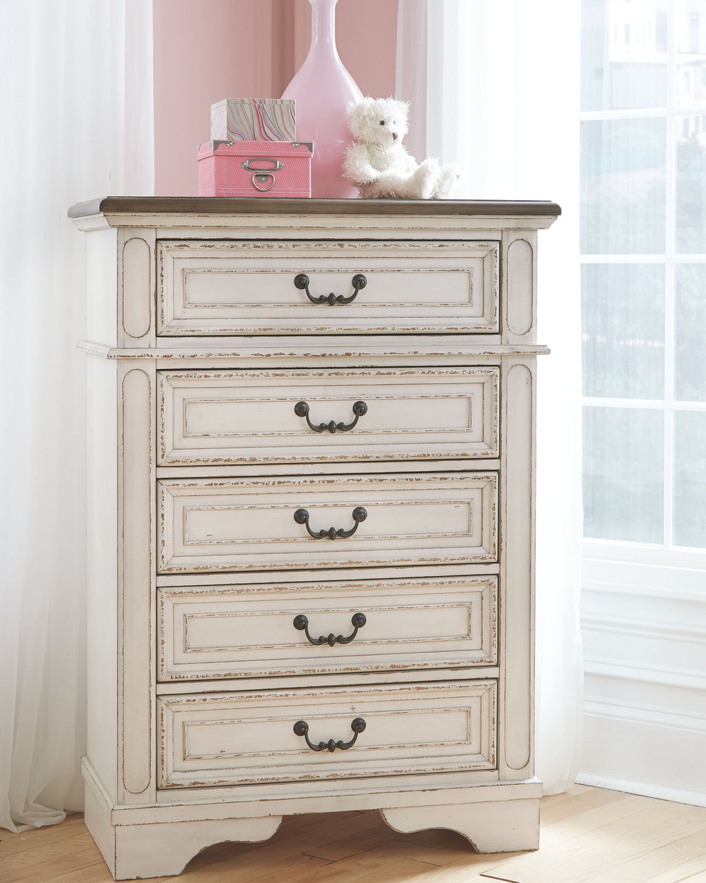 Chipped white chest of drawers with four drawers and dark curved knobs