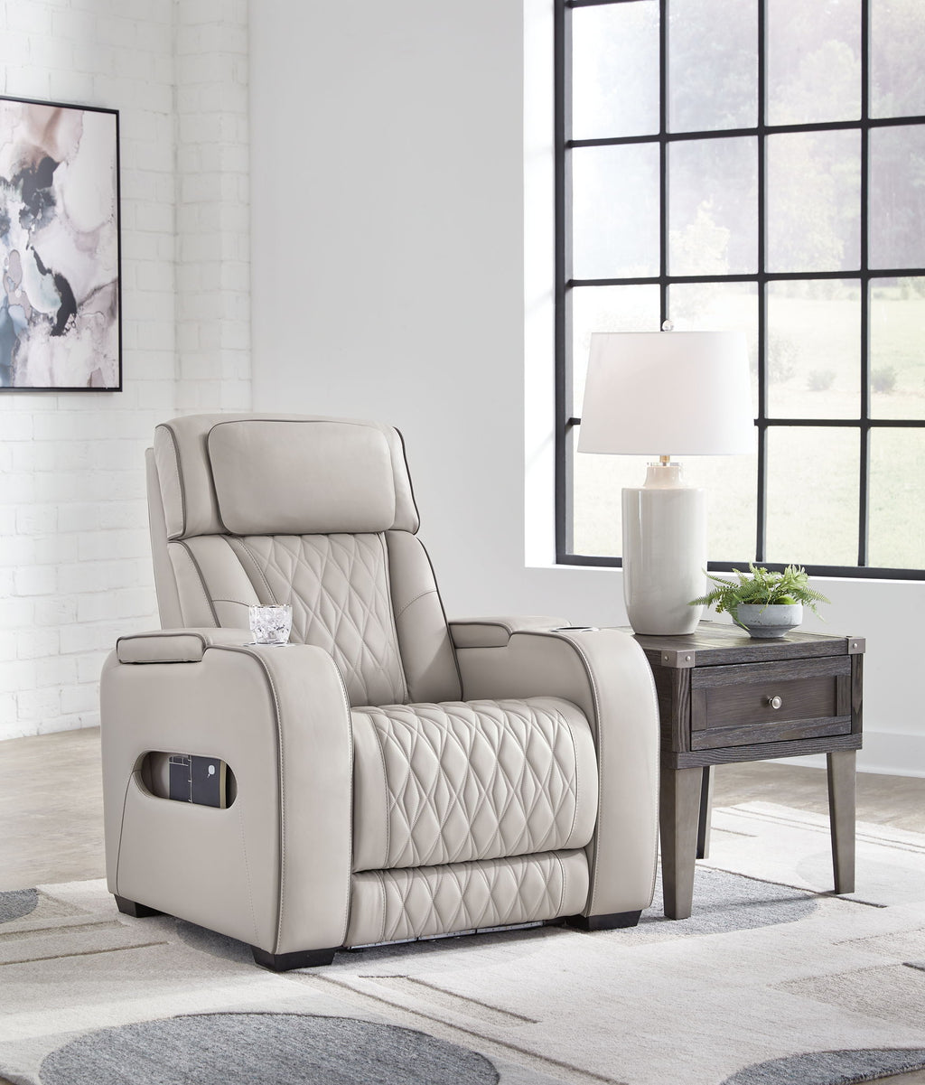 Gray power recliner in living room view, with adjustable headrest and quilted backrest