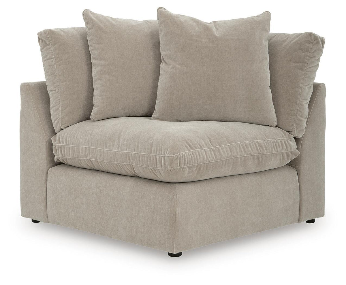 Beige sectional chair with three throw pillows and tufted seat cushion