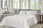 Dark gray sleeper sectional sofa with chaise, featuring an unfolded bed and white comforter
