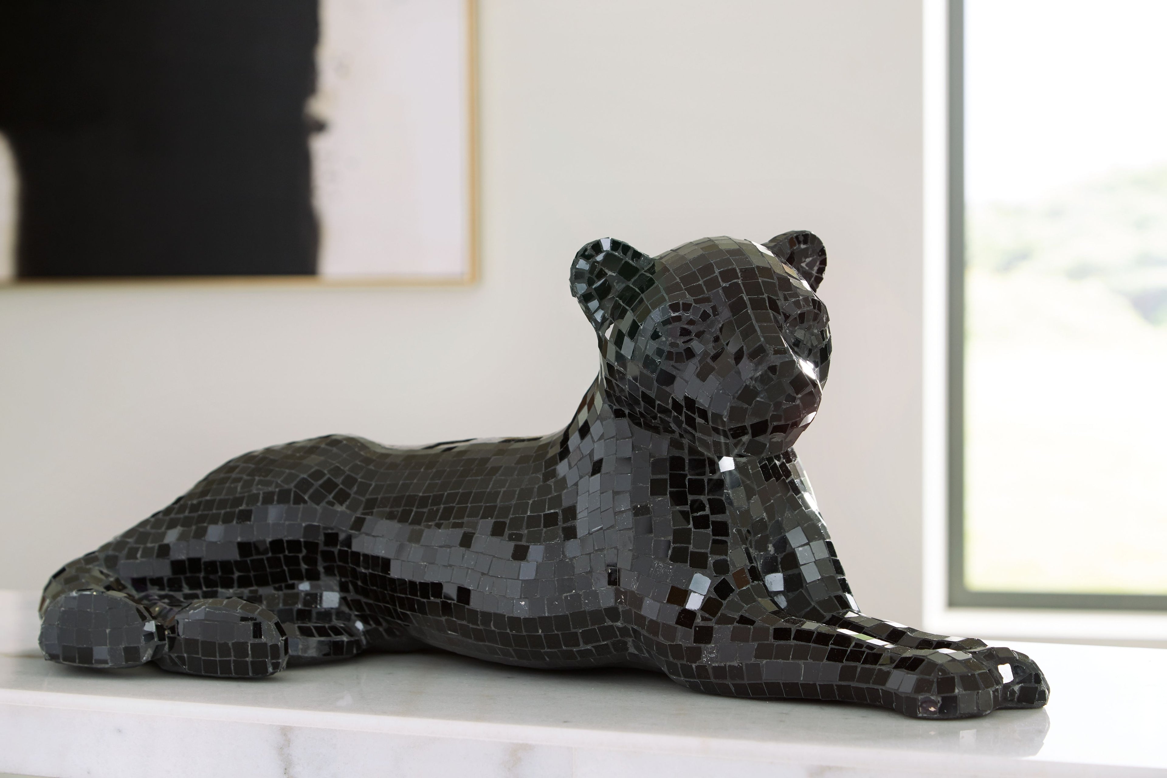 Black mosaic bear sculpture resting on its side