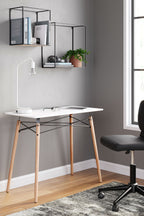 Jaspeni home office desk with white tabletop and light wood legs, black cross-braced frame