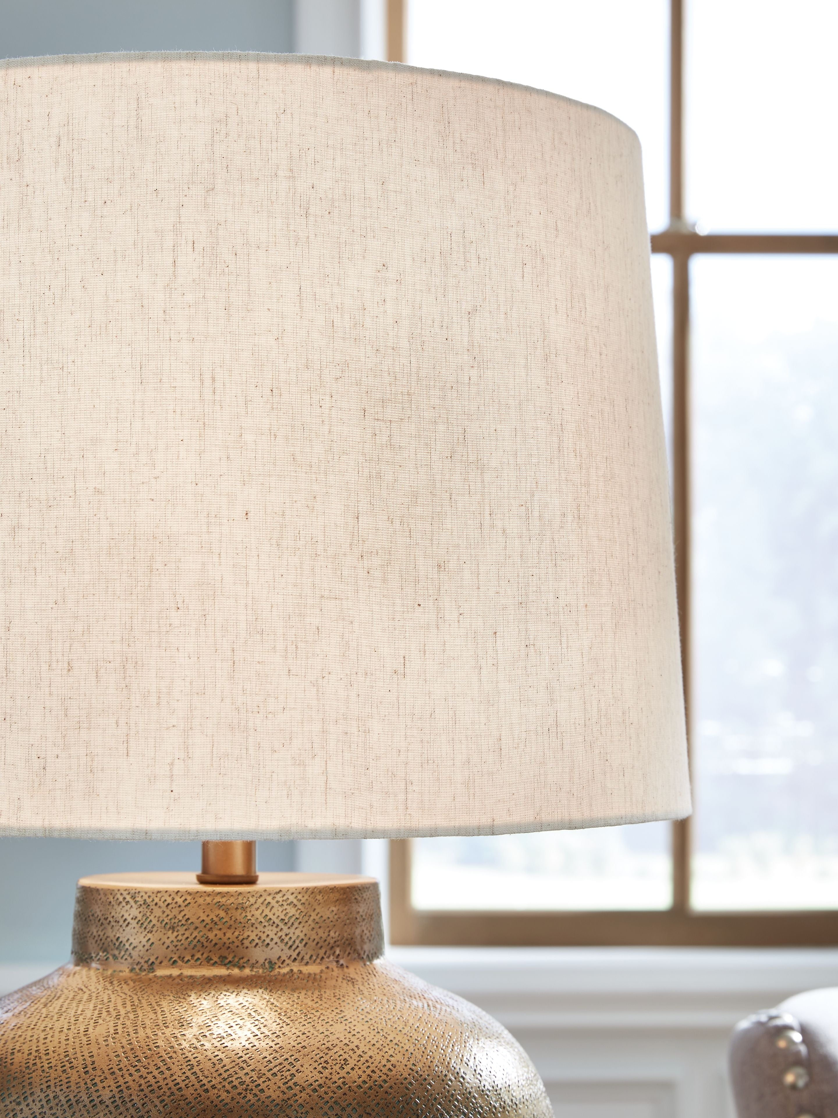 Antique gold metal lamp base under beige fabric drum shade