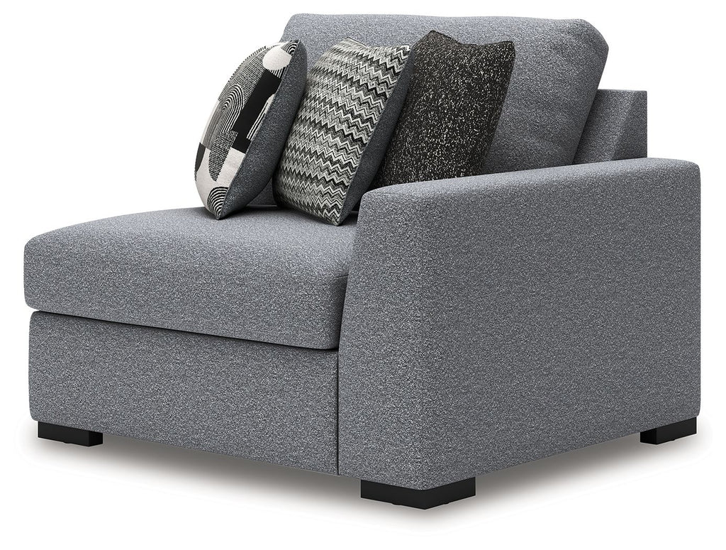 Gray corner accent chair with thick padded arms and two patterned throw pillows