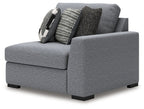 Gray corner accent chair with thick padded arms and two patterned throw pillows