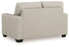 Light beige leather-look loveseat with tufted back and smooth seat, visible arm panel