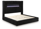 Black upholstered bed with ribbed frame and lit fireplace screen