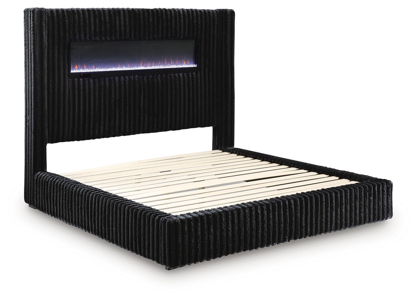 Black upholstered bed with ribbed frame and lit fireplace screen