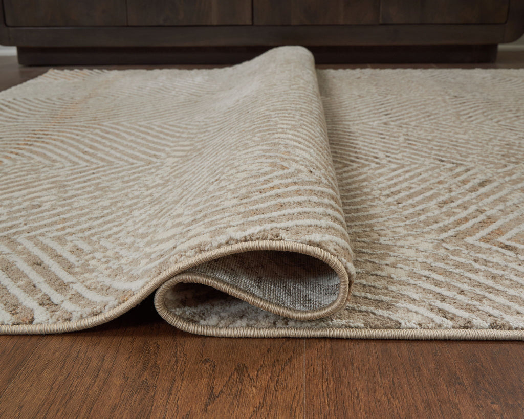 Beige rug with geometric weave and visible rolled edge, low pile texture