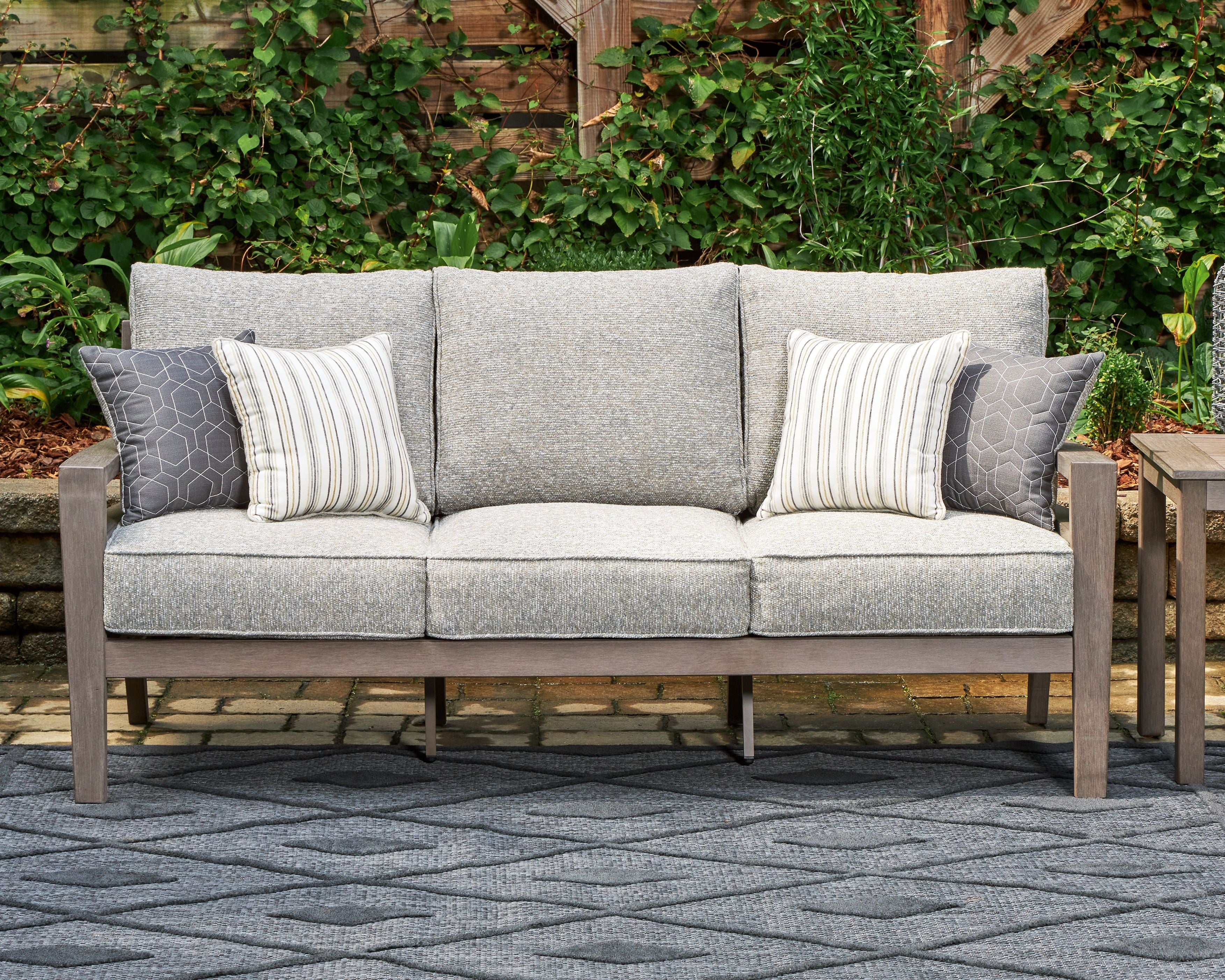 Gray outdoor sofa with two side throw pillows, striped and patterned cushion inserts