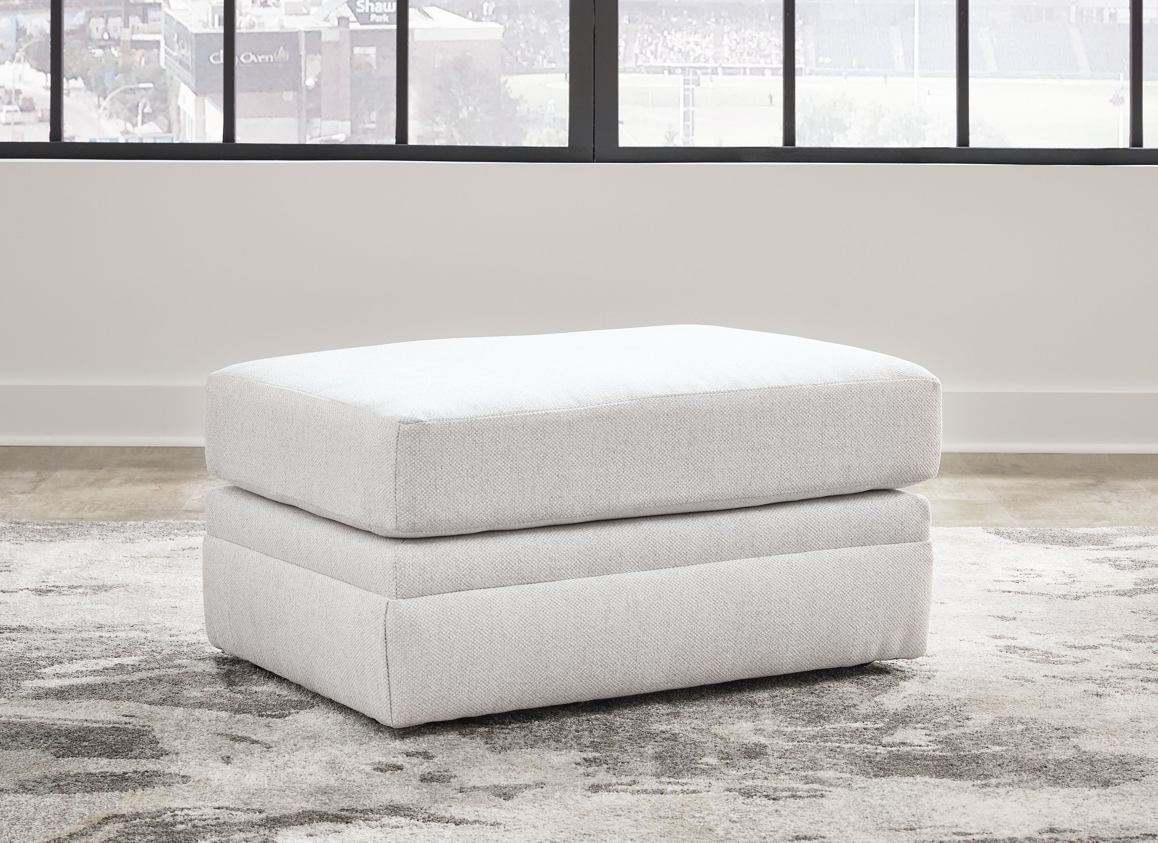 Light beige ottoman with two-tier cushioned base and rounded top, short legs